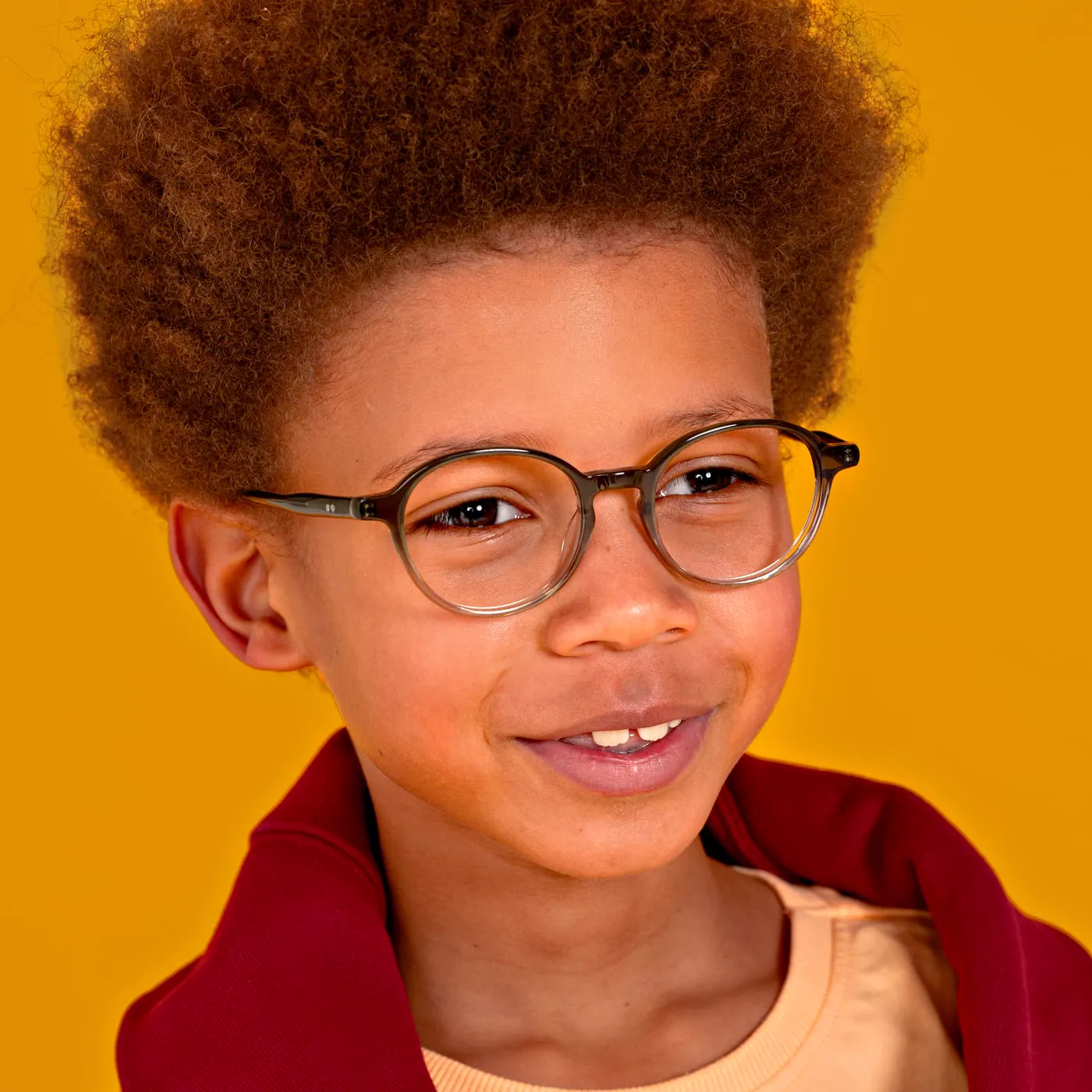 Jongen met een kinderbril van BBIG, voor een gele achtergrond