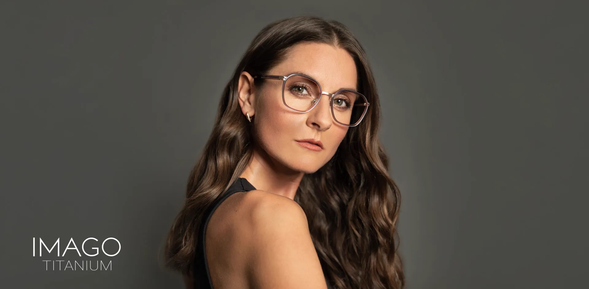 Lachende vrouw met een bril van Imago, voor een roze achtergrond