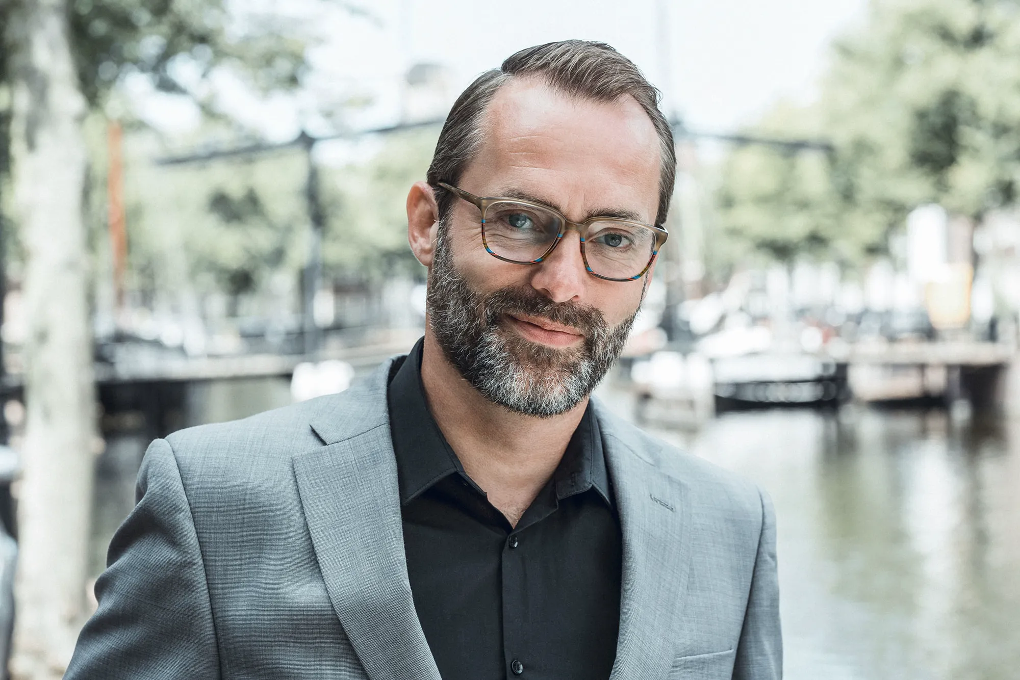 Man met baard en een bril van Johann von Goisern aan een gracht