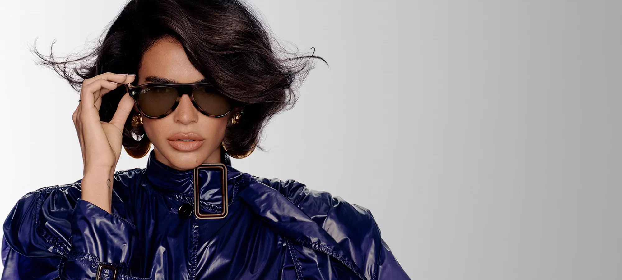 Vrouw met een zonnebril van Ray-Ban en een glanzende jas